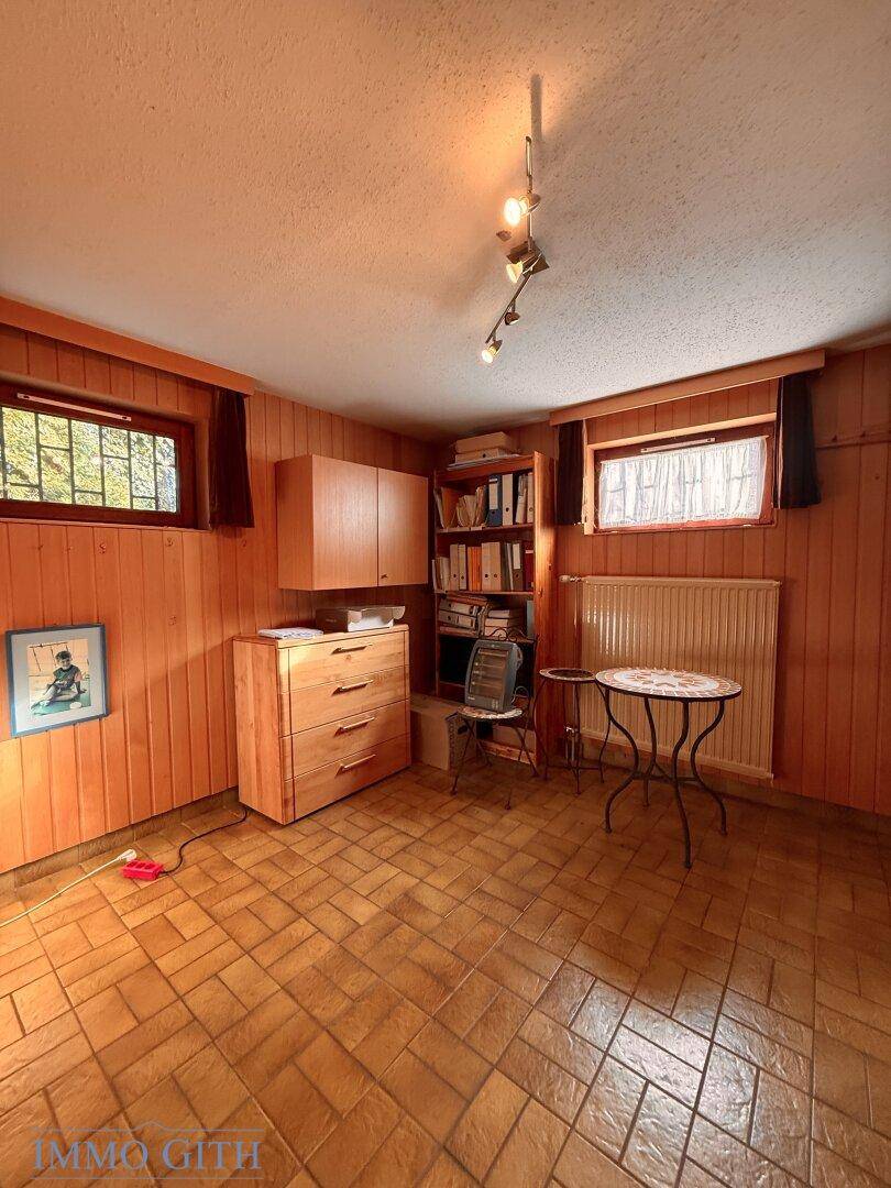 Kleines Arbeitszimmer mit Holzvertäfelung, Fliesenboden und Fenster.