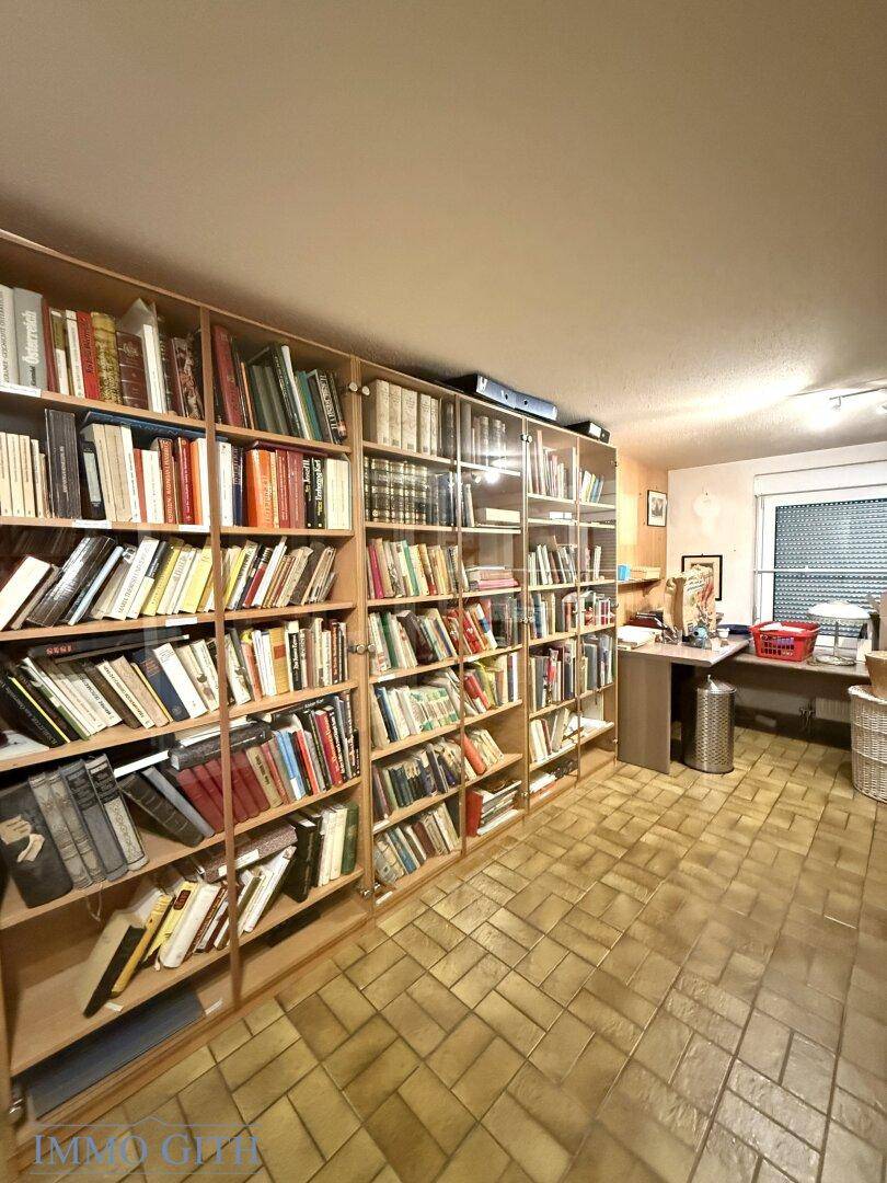 Geräumiges Arbeitszimmer mit großen Bücherregalen und Fliesenboden.
