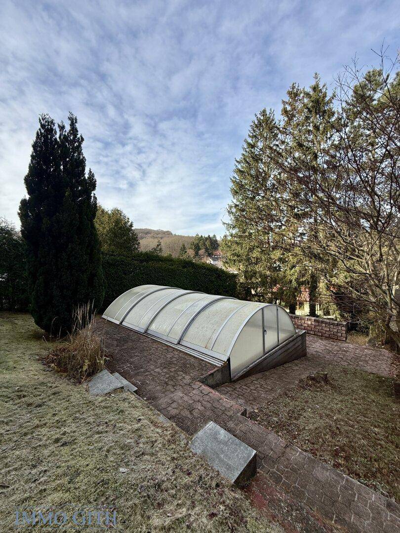 Gartenbereich mit überdachtem Pool und umliegender Grünfläche.