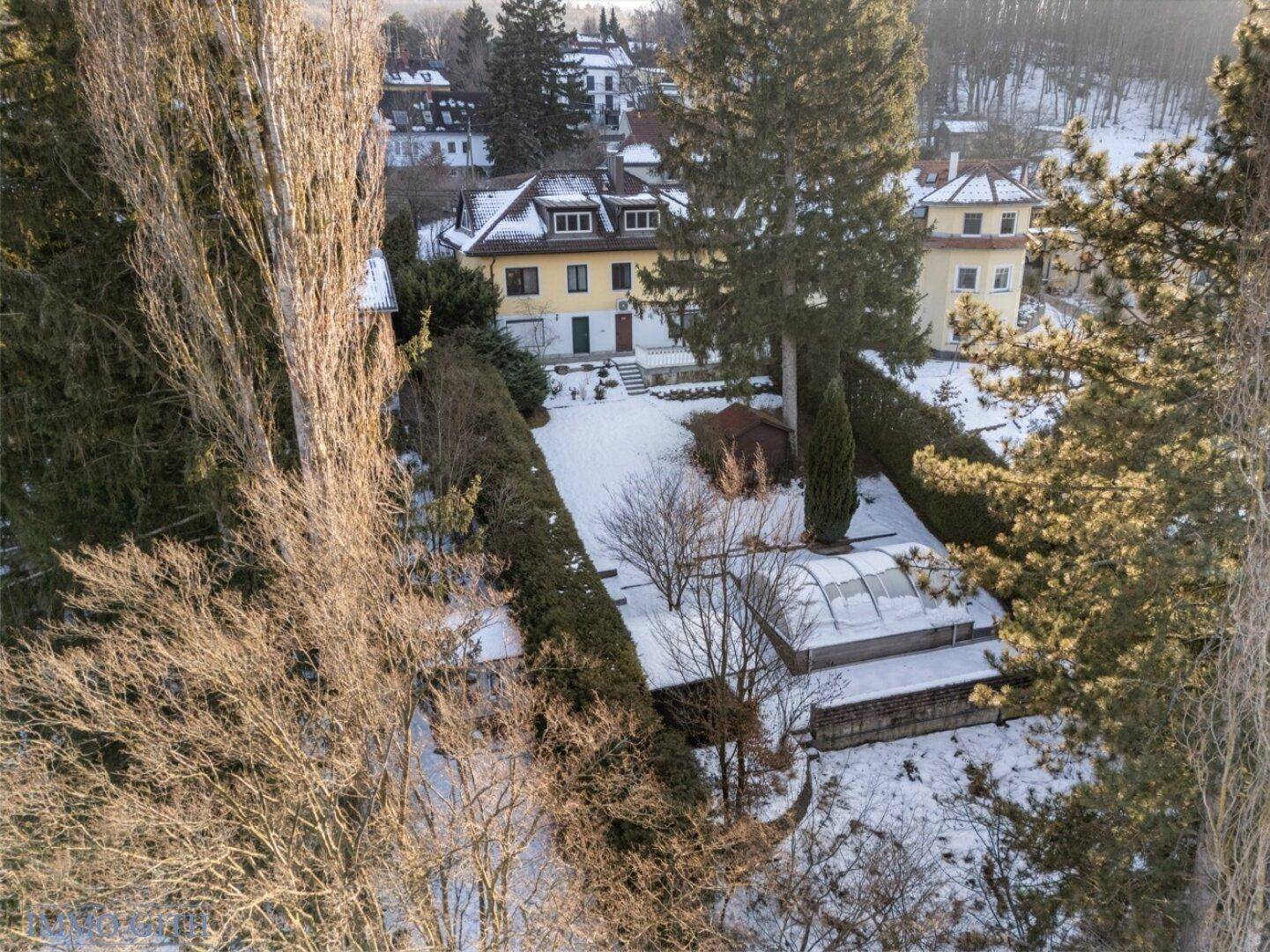 Weitläufiger Gartenbereich mit Pool und Gartenhaus, umgeben von hohen Bäumen im Winter.