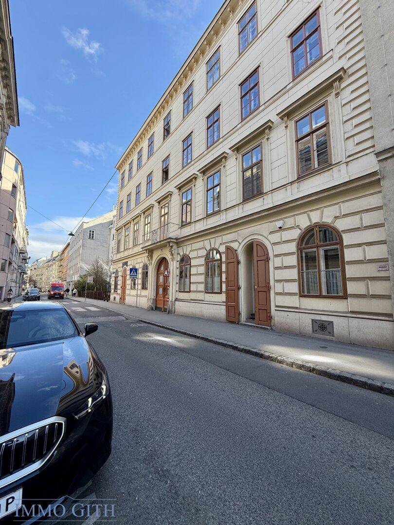 Historisches Gebäude mit klassischer Fassade und Holztüren an einer städtischen Straße.