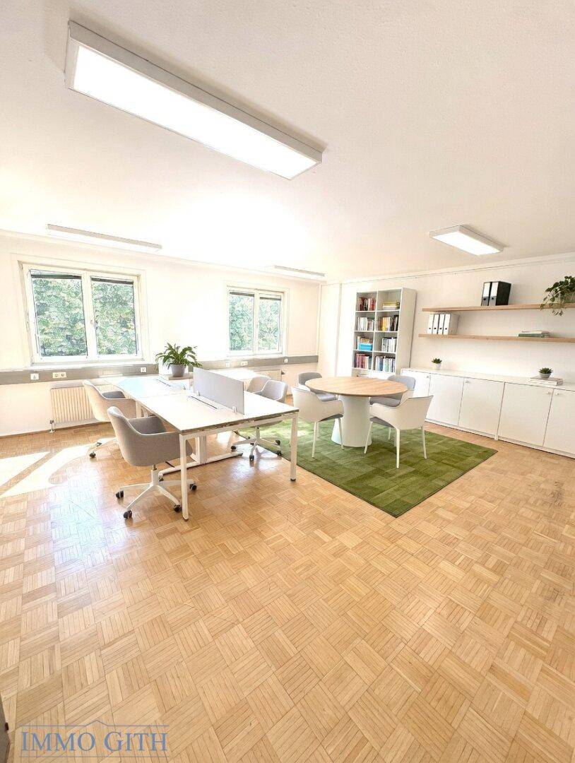 Großes Gemeinschaftsbüro mit mehreren Arbeitsplätzen, Besprechungstisch und Blick ins Grüne.