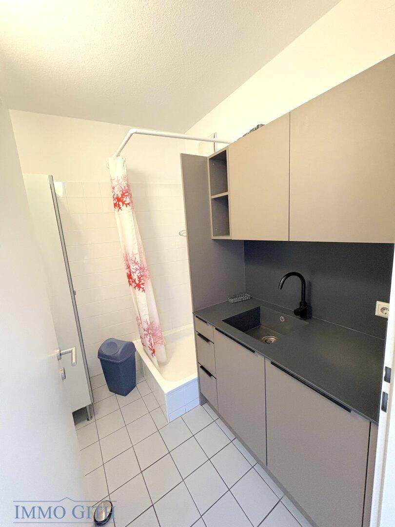 Kleines Badezimmer mit Dusche, Waschbecken und Fliesenboden, funktional und sauber.