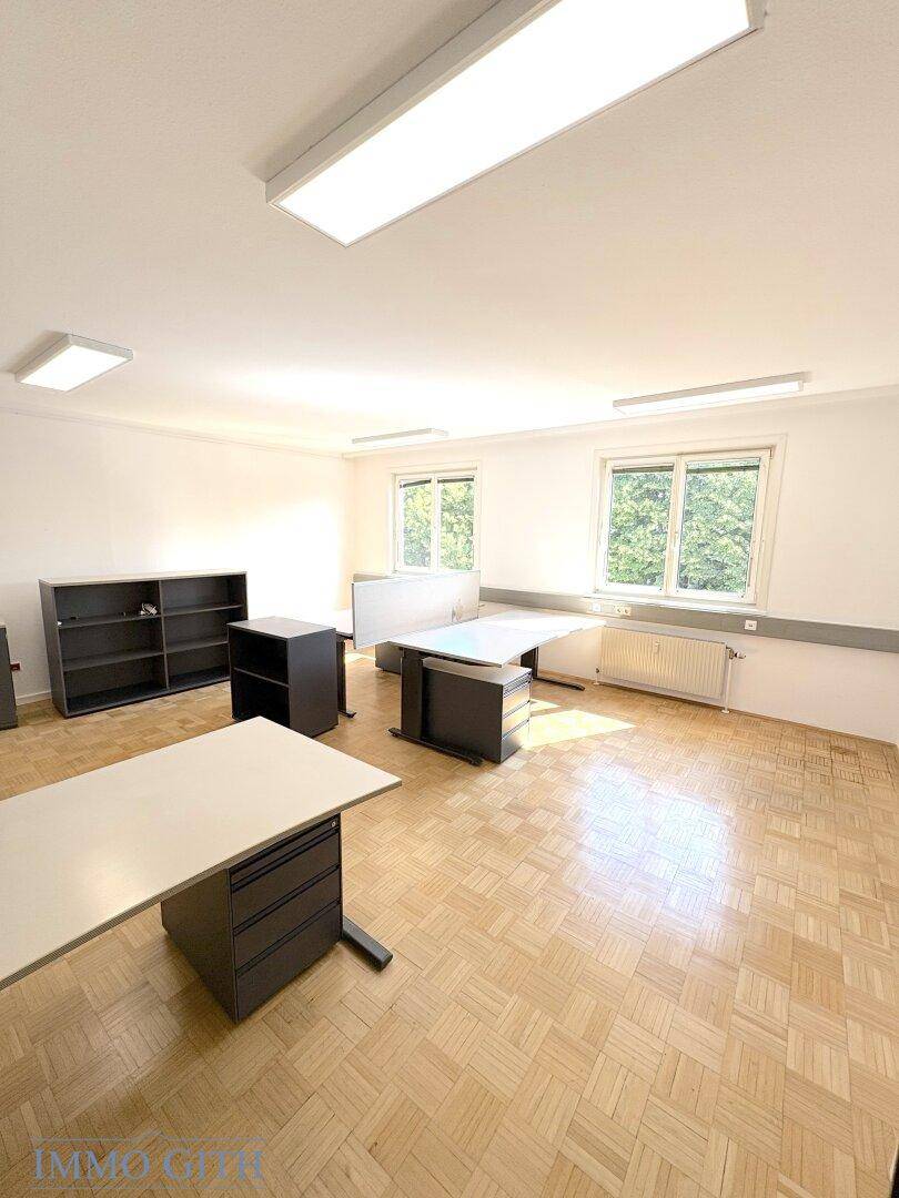 Geräumiger Büroraum mit Holzboden, Fenstern und flexiblen Arbeitsplatzlösungen.