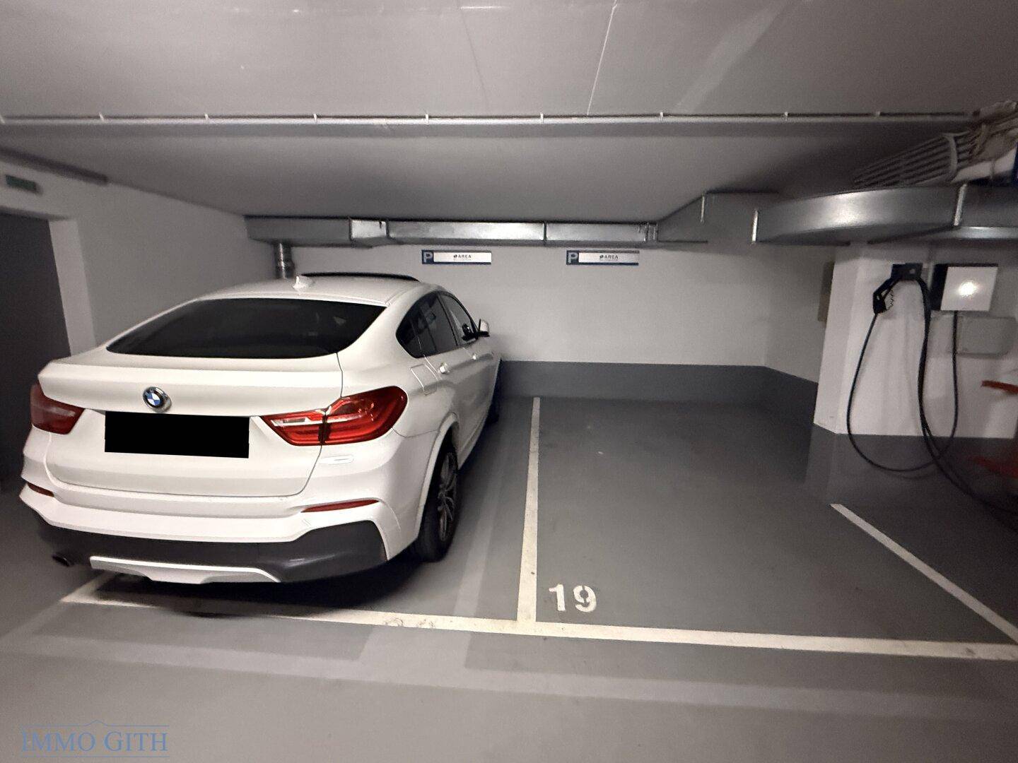 Moderner Tiefgaragenstellplatz mit Lademöglichkeit für Elektroautos und sauberem Betonboden.