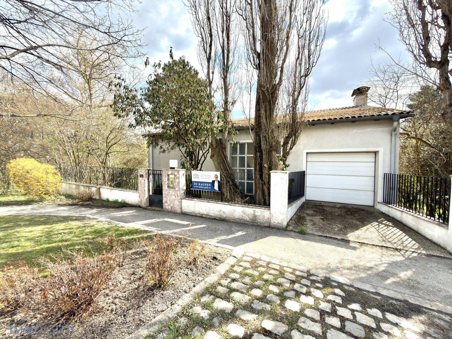 Vorderansicht des Hauses mit Garage, Einfahrt und Zaun von der Straße aus gesehen.