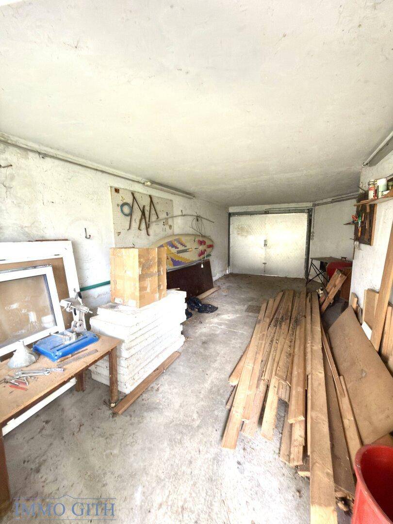 Geräumige Garage mit Betonboden, Lagerflächen und einem Garagentor.