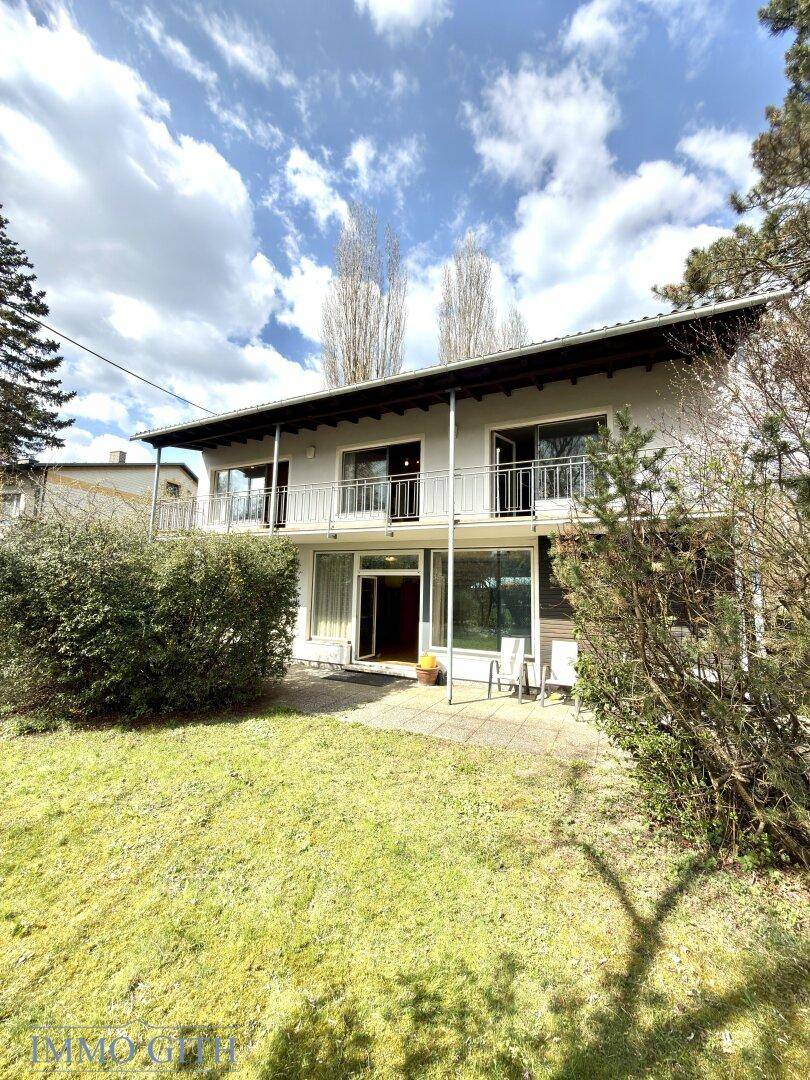 Rückansicht des Hauses mit großer Terrasse, Balkonen und Zugang zum Garten.