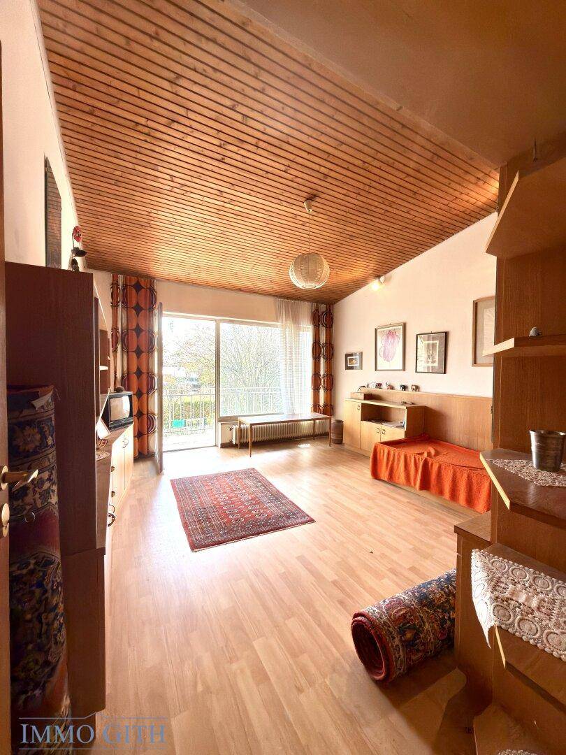 Helles Zimmer mit Holzdecke, Parkettboden und Zugang zu einem Balkon mit Aussicht.
