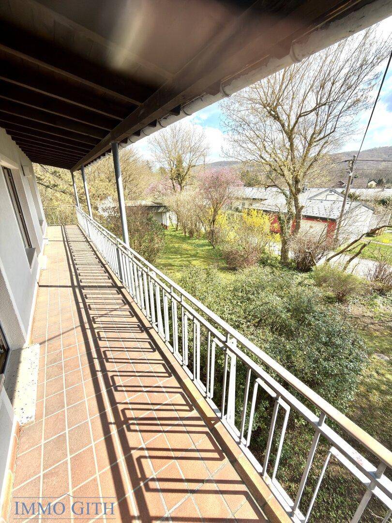 Langer Balkon mit Fliesenboden und Metallgeländer, bietet weite Aussicht auf die Umgebung.