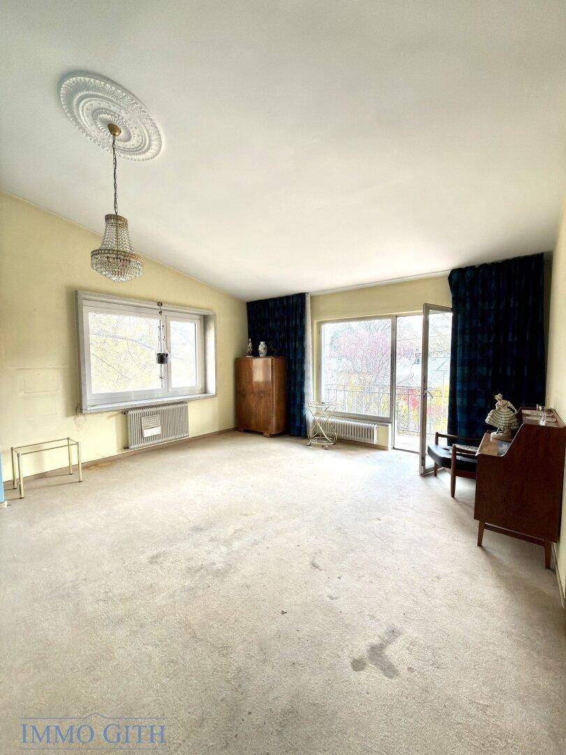 Großes Zimmer mit Teppichboden, Stuckdecke und Zugang zu einem französischen Balkon.