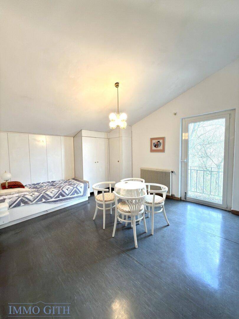 Helles Schlafzimmer mit dunklem Boden, Einbauschränken und Zugang zu einem Balkon.