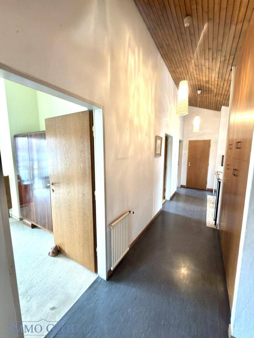 Langer Flur mit Holzdecke, dunklem Boden und Zugang zu verschiedenen Zimmern.