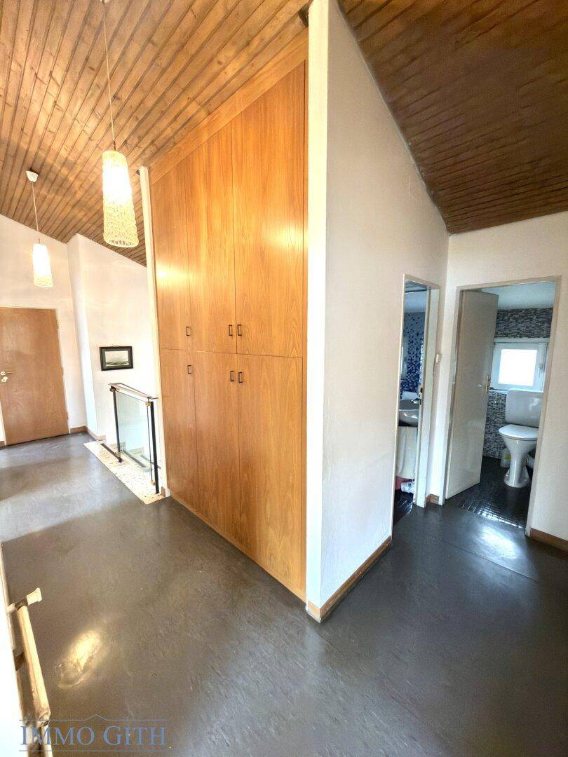 Flur mit Holzdecke, Einbauschränken und Zugang zu einem Badezimmer.