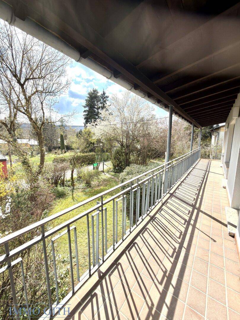 Geräumiger Balkon mit Fliesenboden und weitem Blick über die grüne Landschaft.