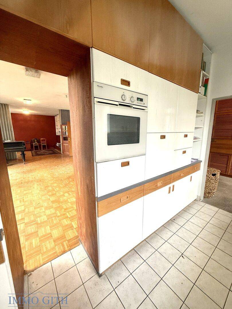 Kücheneingang mit Einbauschrank, integriertem Backofen und Fliesenboden.
