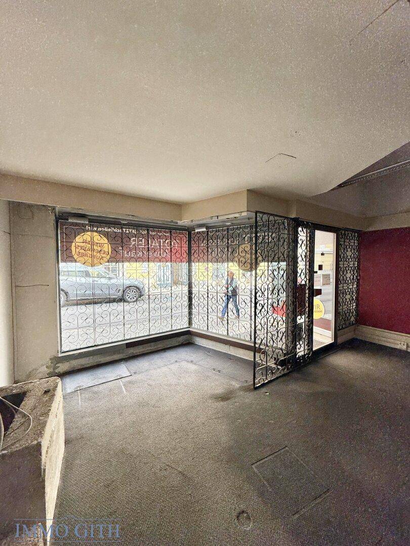 Leerer Eingangsbereich eines Geschäfts mit großen Schaufenstern und dekorativen Metallgittern.
