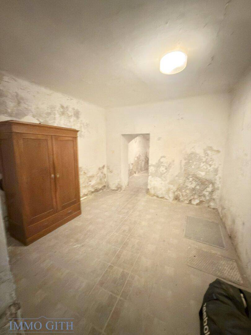 Raum in schlechtem Zustand mit abblätternder Farbe an den Wänden und einem alten Schrank.
