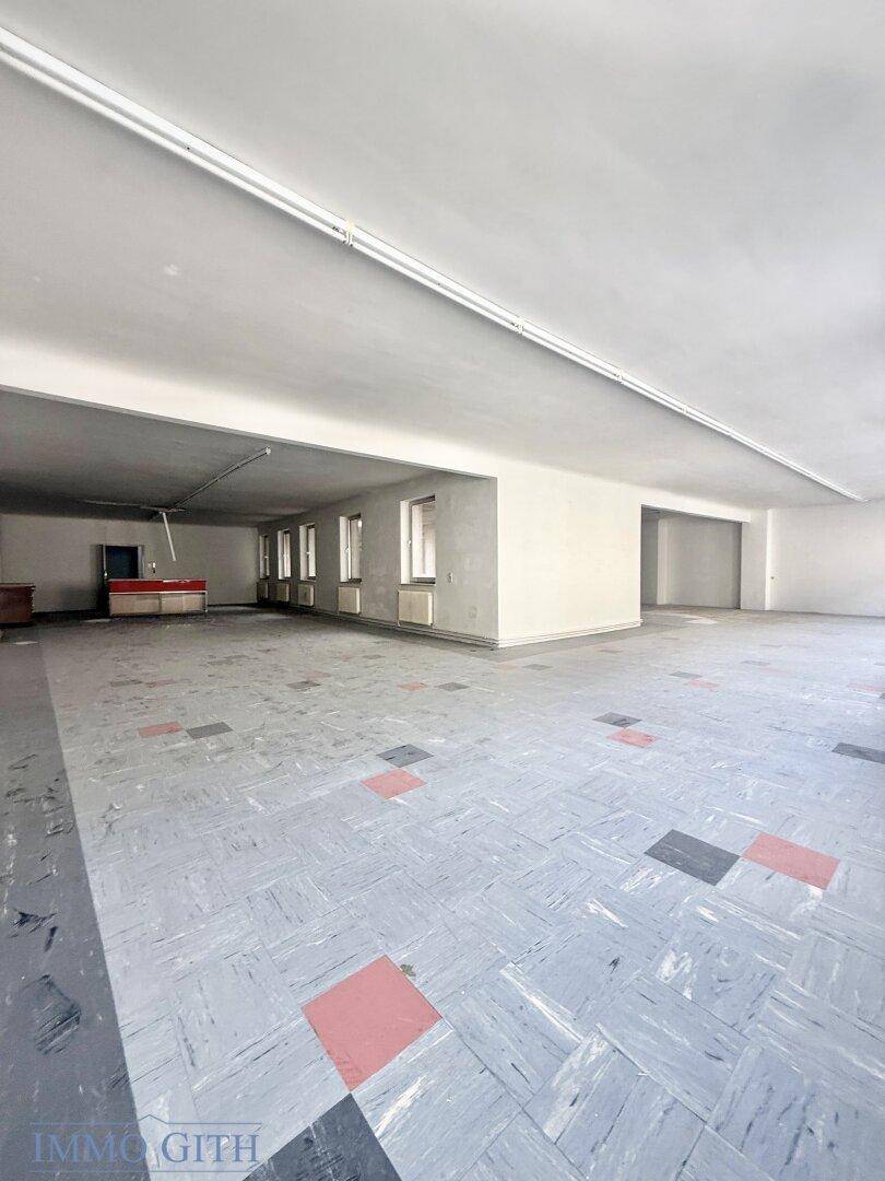 Großer, leerer Raum im Obergeschoss mit Fenstern und einem gemusterten Fliesenboden.