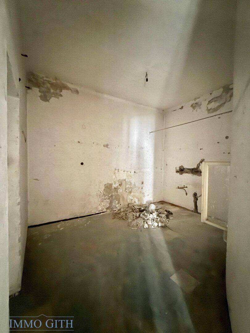 Kleiner, unfertiger Raum mit kahlen Wänden und Bauschutt auf dem Boden, bereit zur Sanierung.
