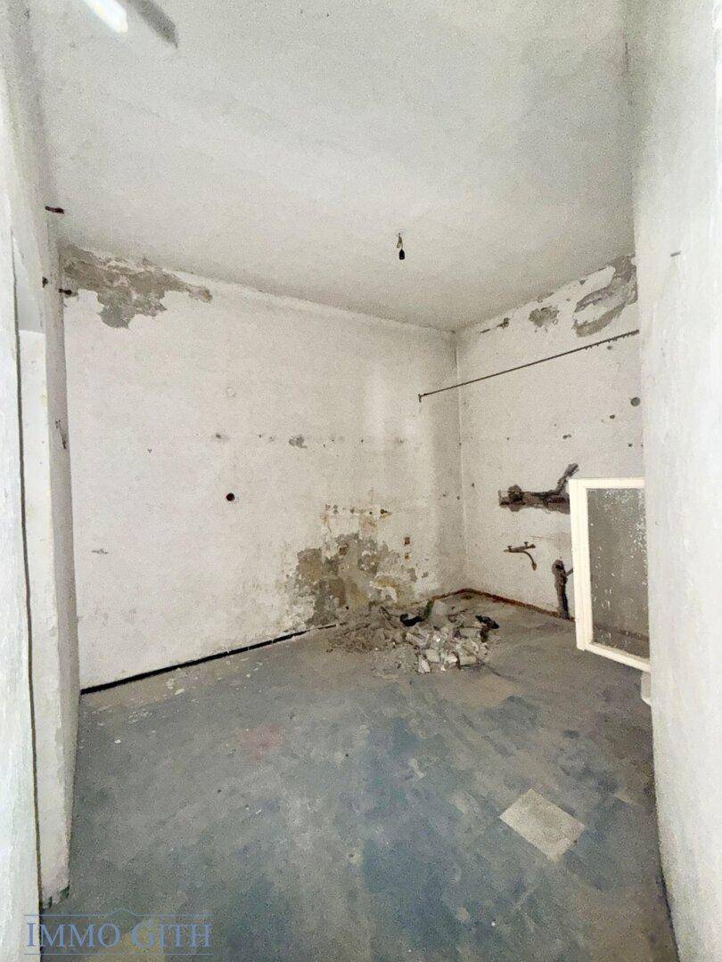 Kleiner, unfertiger Raum mit kahlen Wänden und Bauschutt auf dem Boden, bereit zur Sanierung.