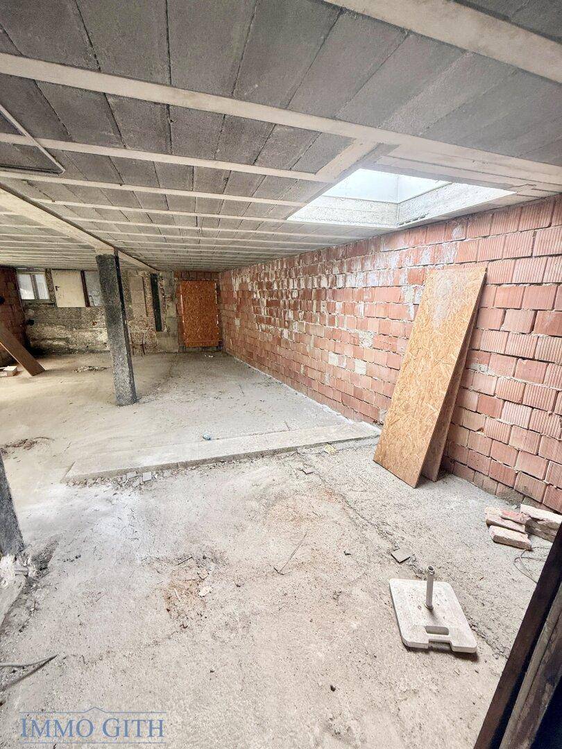 Unfertiger Kellerraum mit Ziegelwänden, Betonboden und sichtbarer Deckenkonstruktion, viel Potenzial.