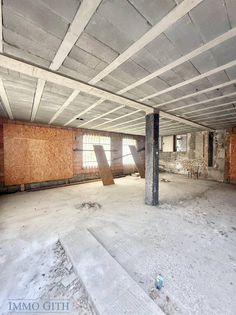 Großer Kellerraum mit Betonstütze, Ziegelwänden und sichtbarer Deckenkonstruktion, unfertig.