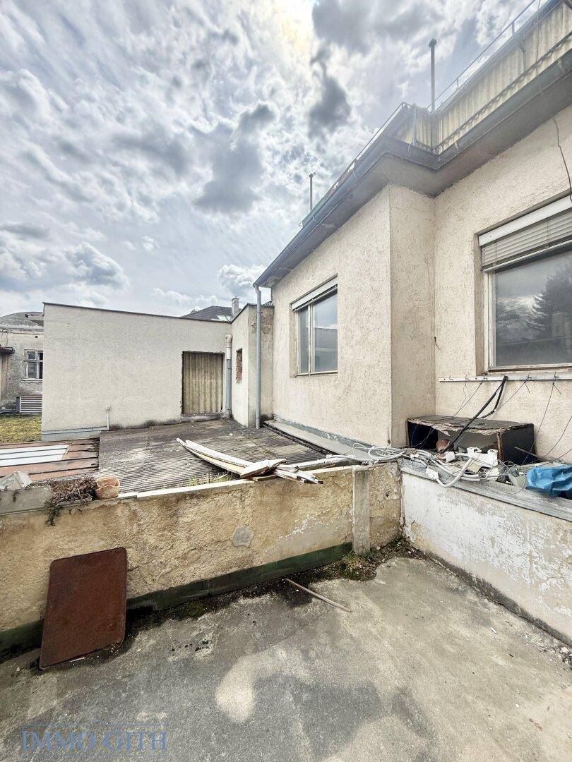 Verwitterte Terrasse an einem Gebäude mit Blick auf die Umgebung, bereit zur Sanierung.