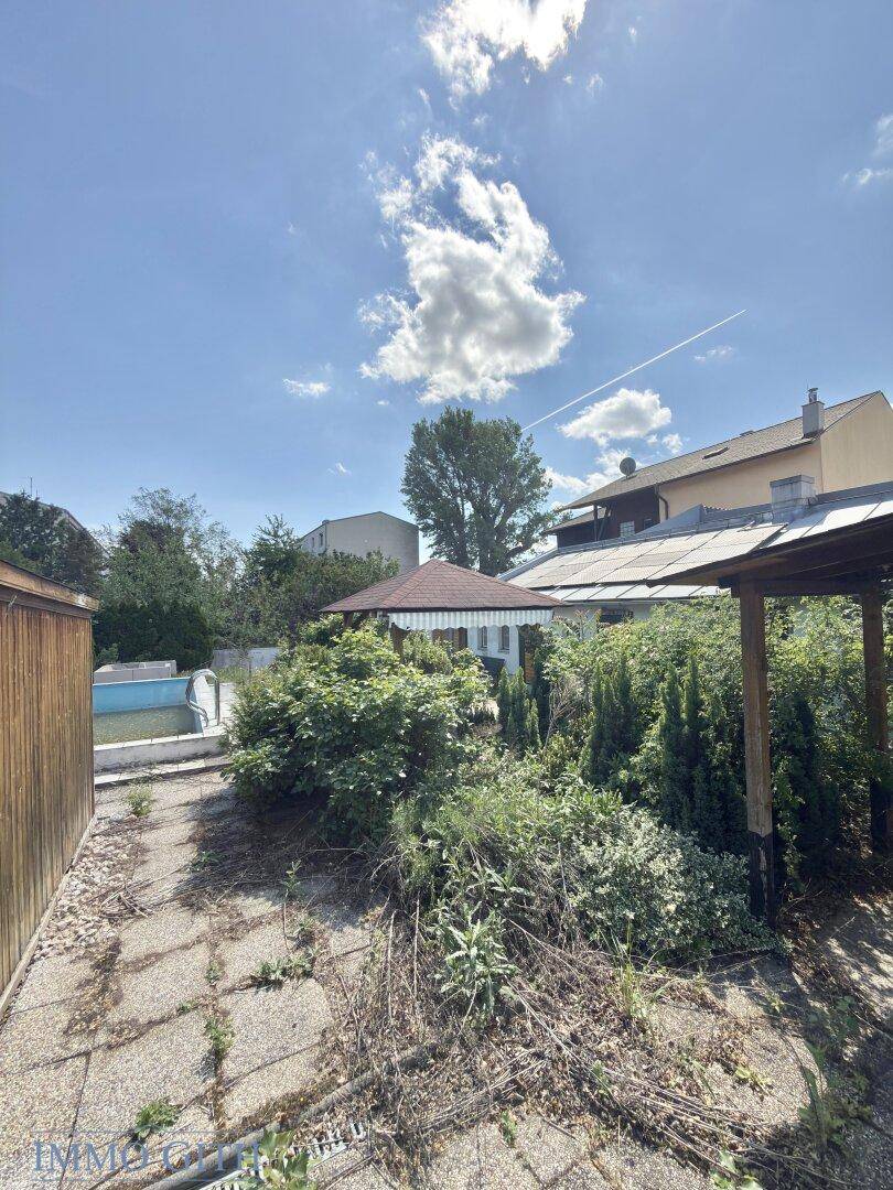 Weitläufiger Gartenbereich mit Pool, Gartenlaube und viel Grün unter blauem Himmel.