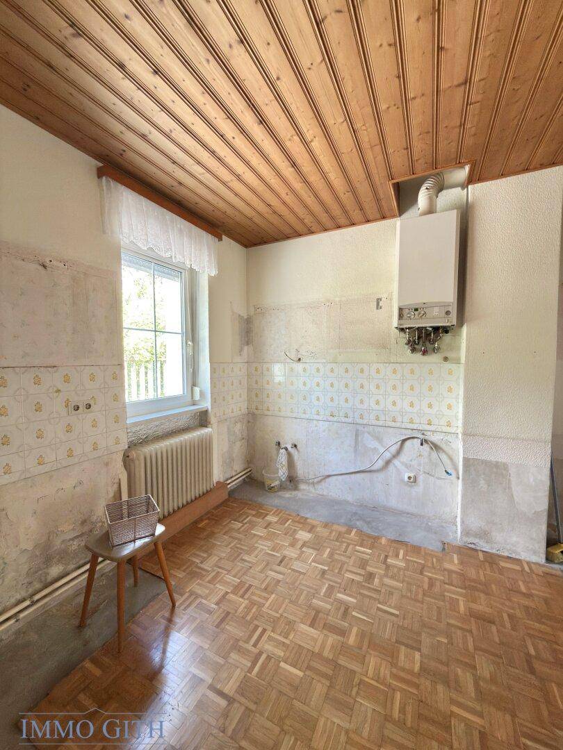 Küche mit Holzdecke und Fliesen an den Wänden, bereit für eine Modernisierung.