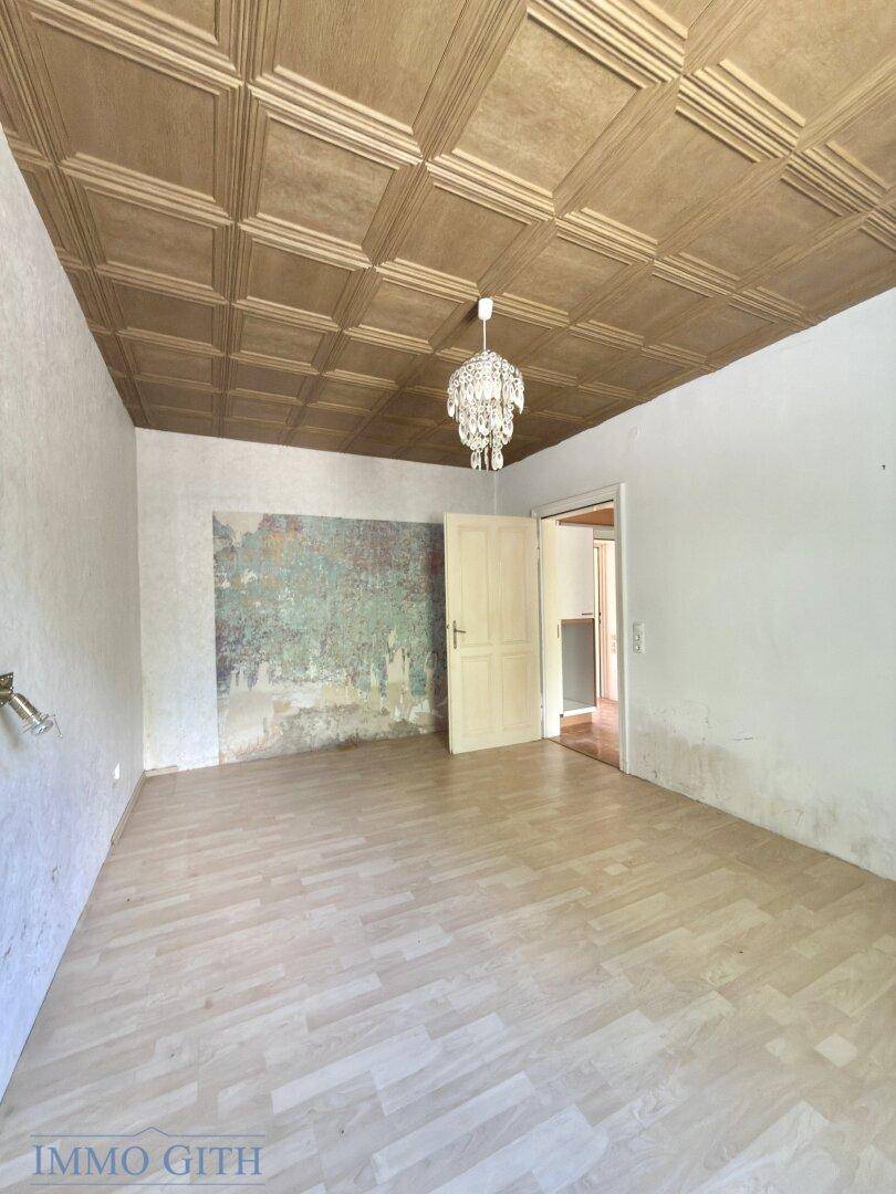Geräumiges Zimmer mit Kronleuchter und dekorativer Wandgestaltung, ideal für ein Schlafzimmer.