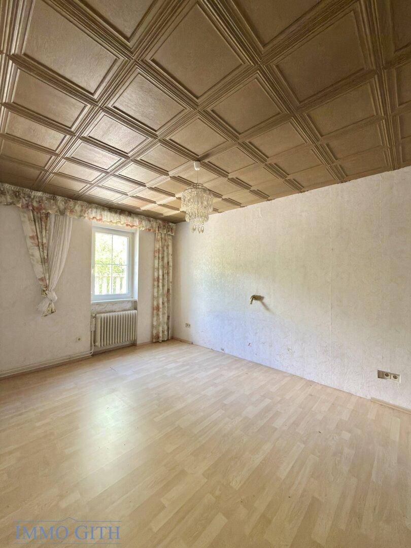Geräumiges Zimmer mit Kronleuchter, Parkettboden und Fenster, ideal für ein Schlafzimmer.