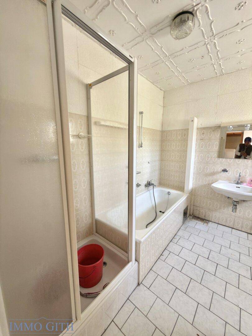 Badezimmer mit Badewanne, Duschkabine und hellen Fliesen an Wänden und Boden.