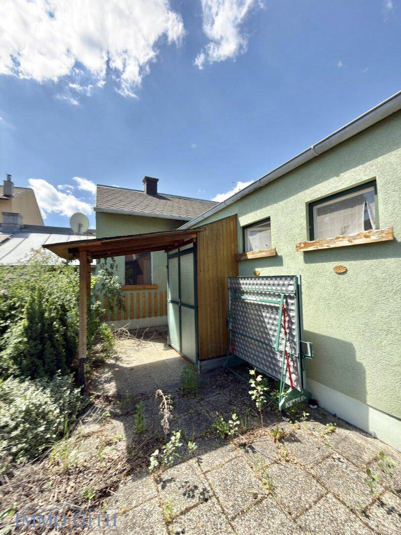 Seitenansicht des Hauses mit überdachtem Eingangsbereich und einer Tischtennisplatte.
