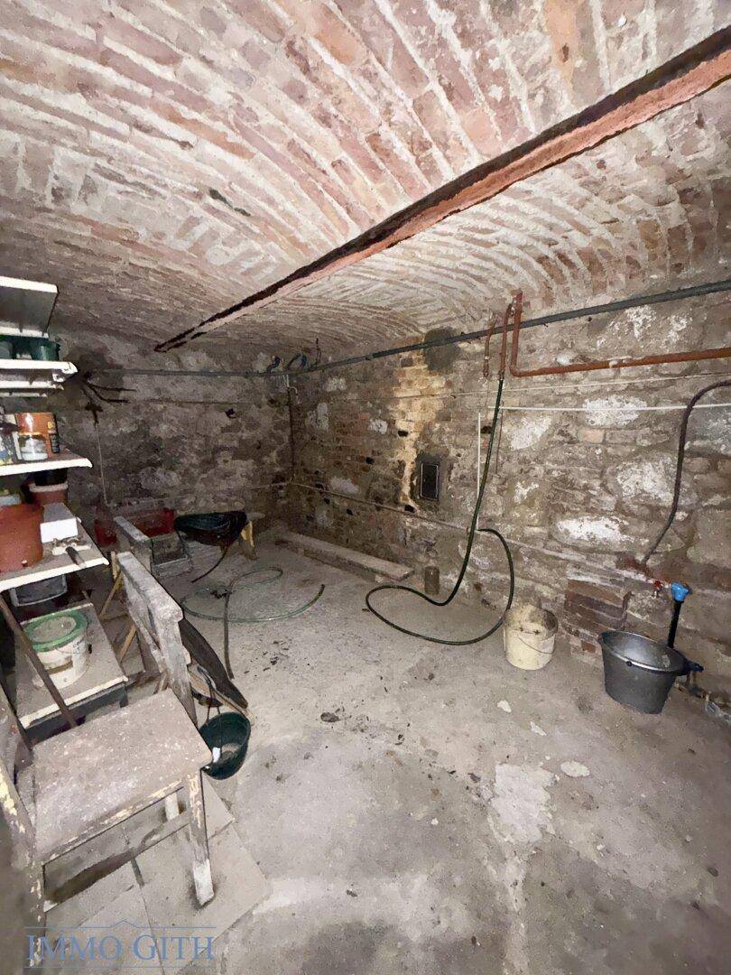 Historischer Gewölbekeller mit Ziegelwänden und einfacher Ausstattung, ideal als Lagerraum.