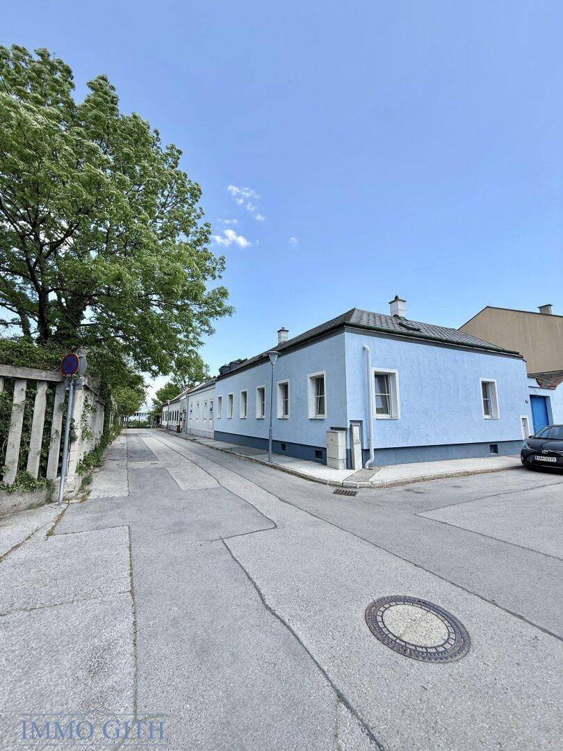 Ruhige Wohnstraße mit einem langen, hellblauen Gebäude unter klarem Himmel.