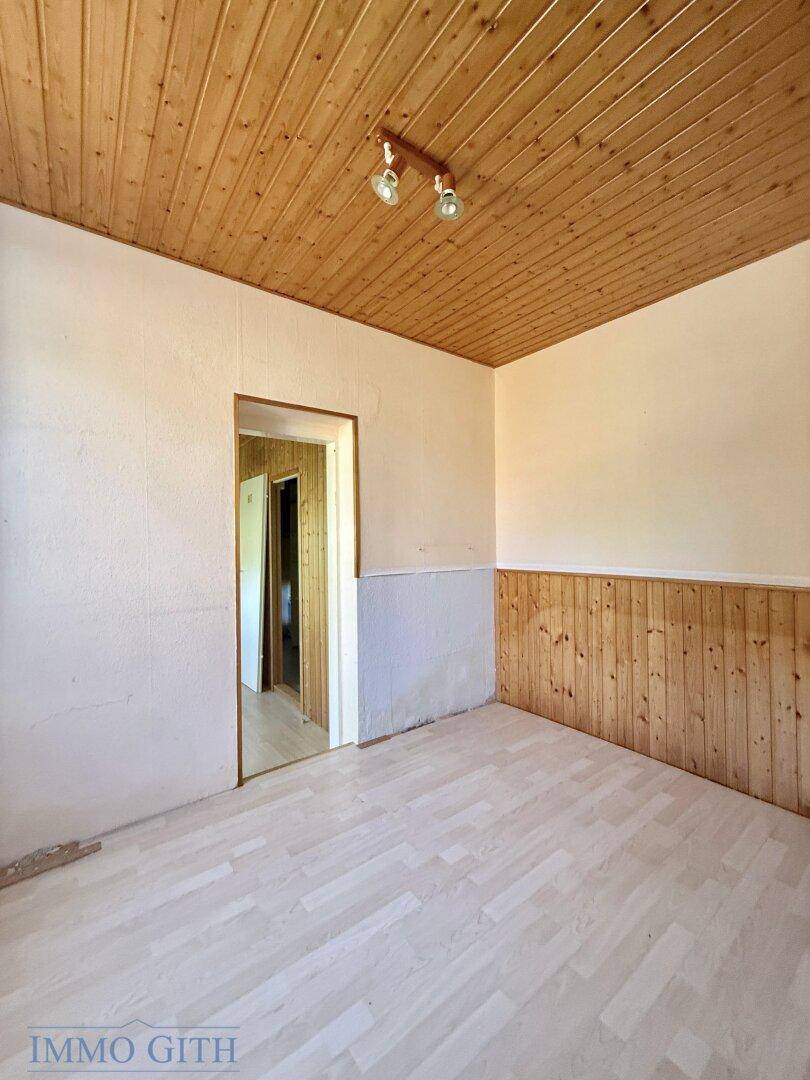 Helles Zimmer mit Holzdecke und Holzvertäfelung, bereit zur individuellen Gestaltung.