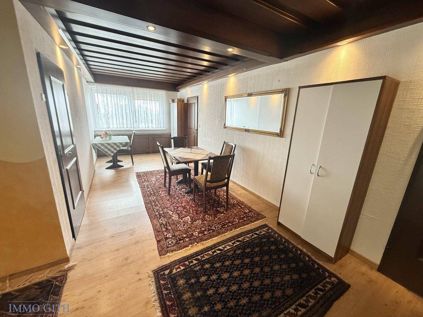 Essbereich mit Holztisch, Stühlen und einem großen Spiegel an der Wand.
