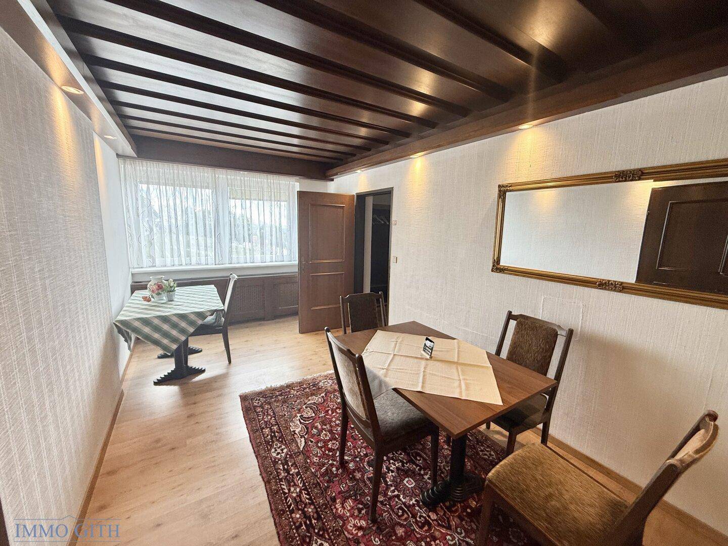 Essbereich mit Holztisch, Stühlen und einem großen Spiegel an der Wand.