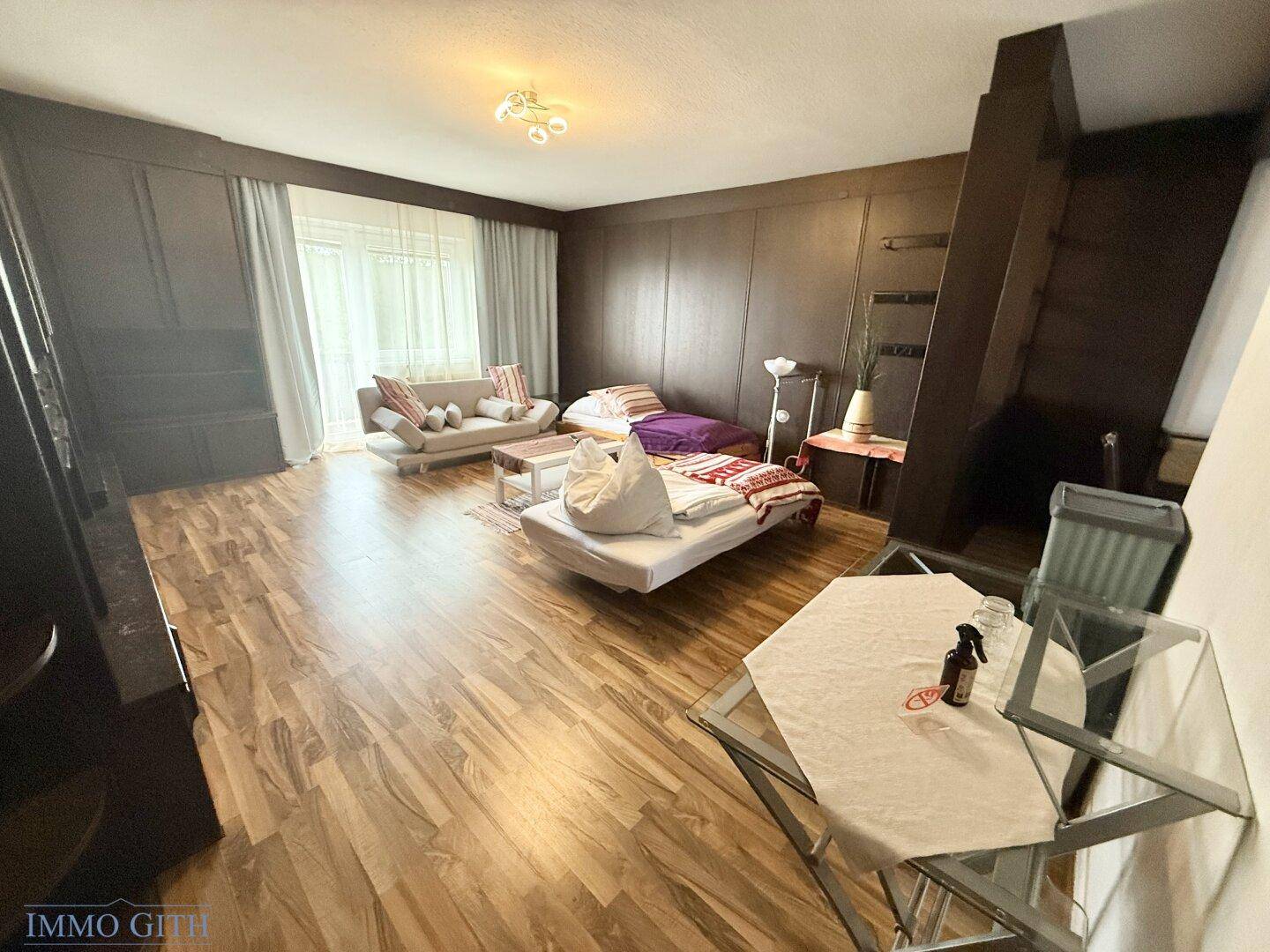 Großzügiger Wohnbereich mit Holzboden, dunklen Holzwänden und mehreren Schlafgelegenheiten.