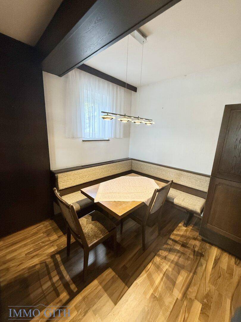 Traditioneller Essbereich mit Eckbank, Holztisch und dunklen Deckenbalken.