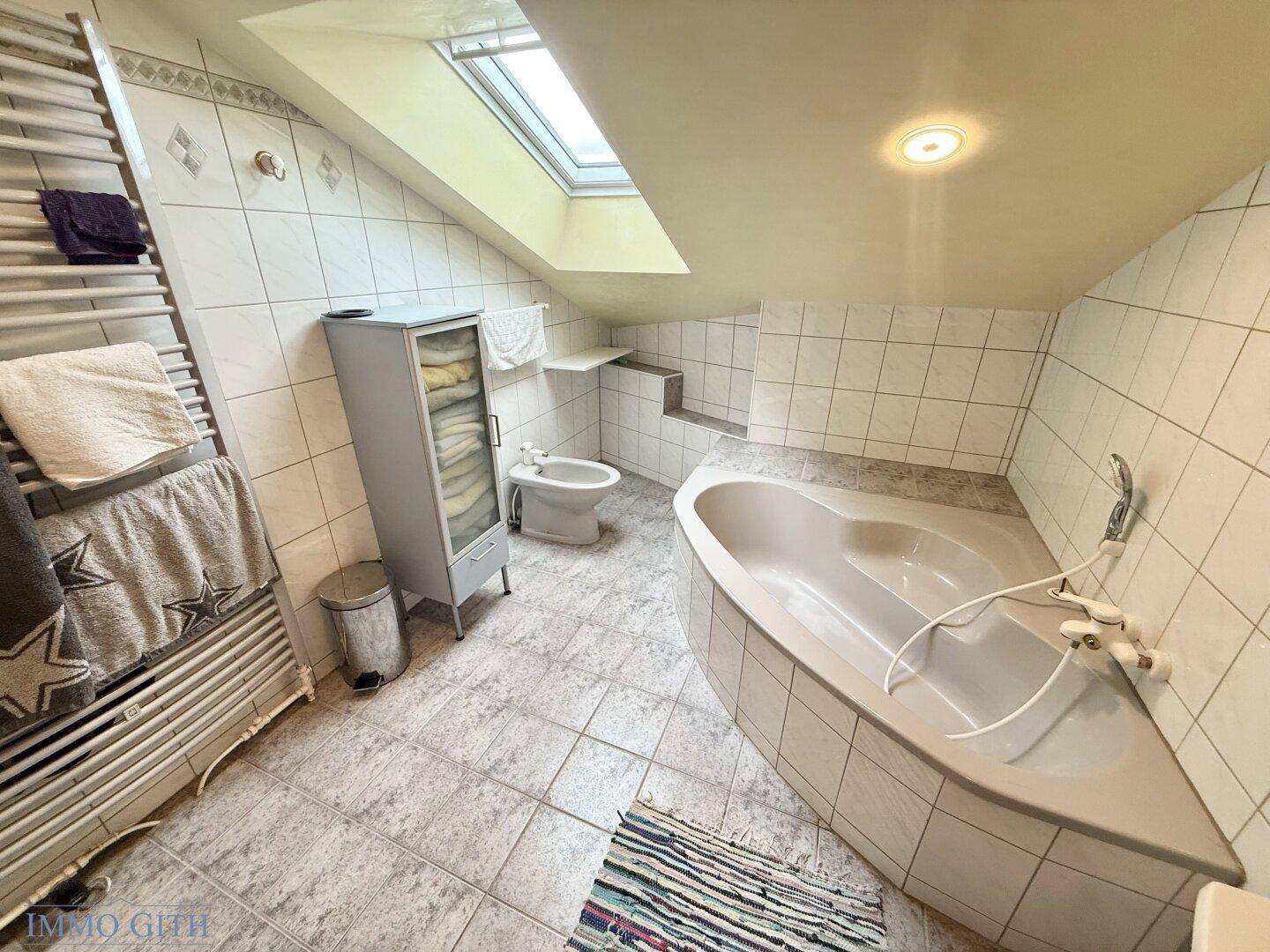 Geräumiges Badezimmer mit Eckbadewanne, Dachfenster und Bidet.