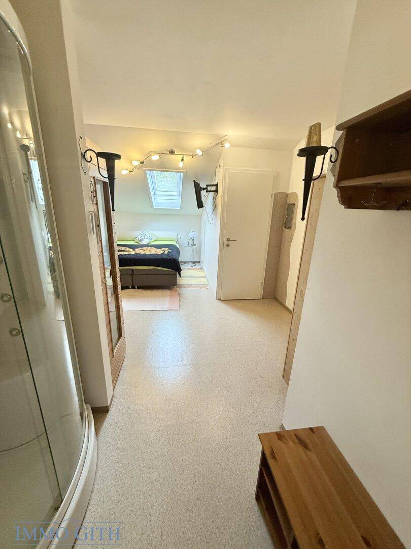 Heller Flur mit Teppichboden, Holzbänken und Blick in angrenzende Räume.