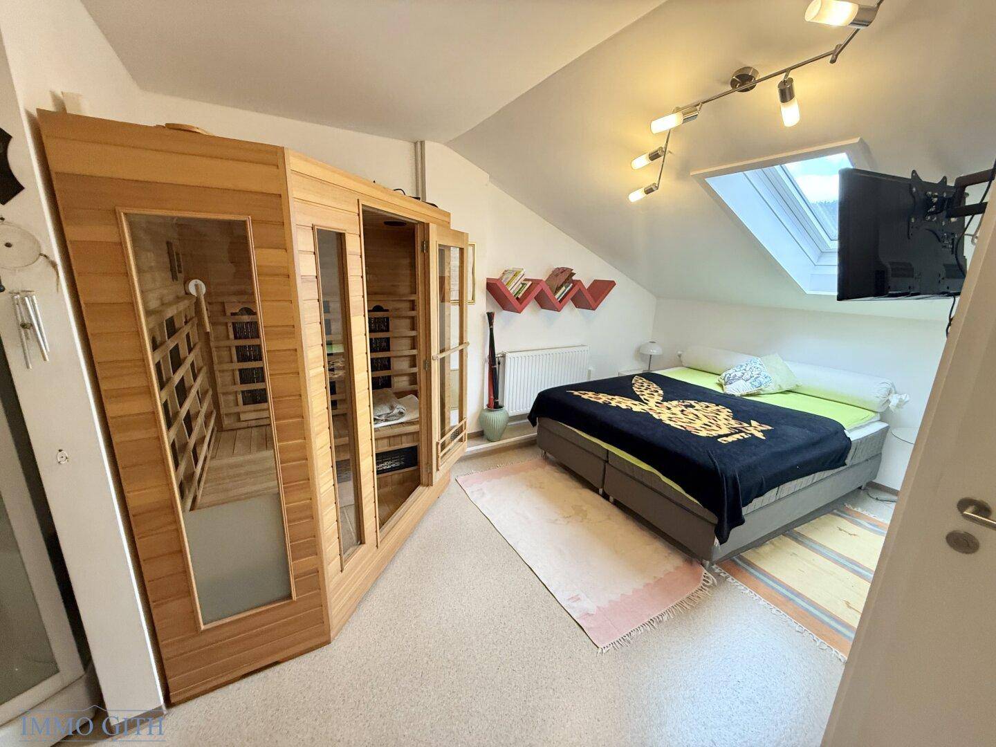 Schlafzimmer mit Teppichboden, Dachschräge, Dachfenster und einer Infrarotkabine.