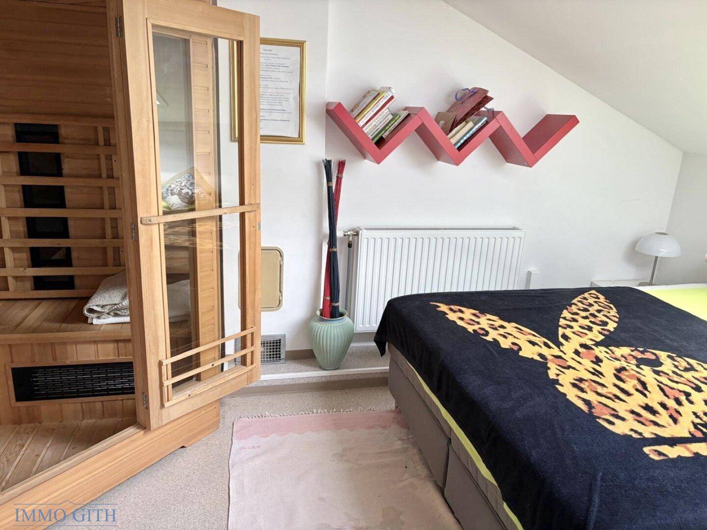 Schlafzimmer mit Doppelbett, einer integrierten Holzsauna und dekorativen roten Regalen an der Wand.