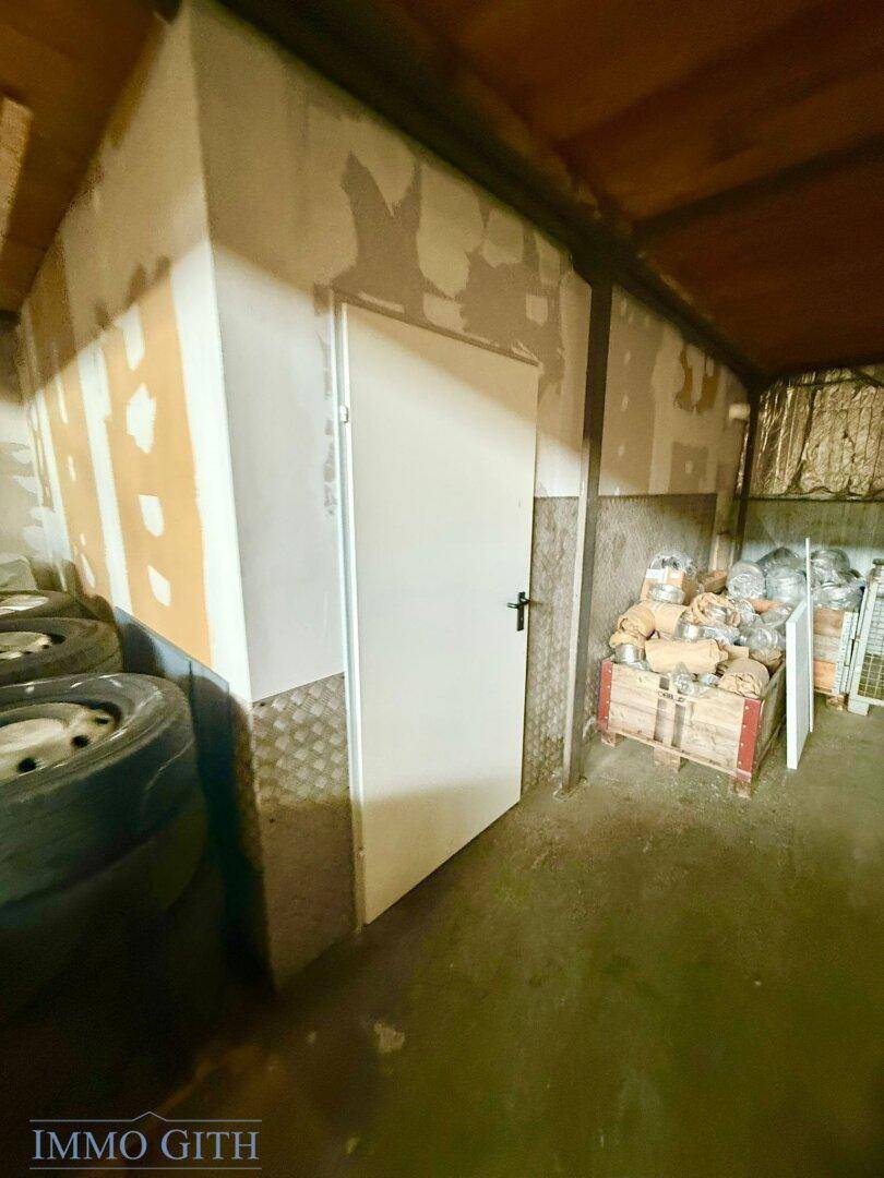 Lagerraum mit einer weißen Tür, gestapelten Materialien und einer unverputzten Wand.