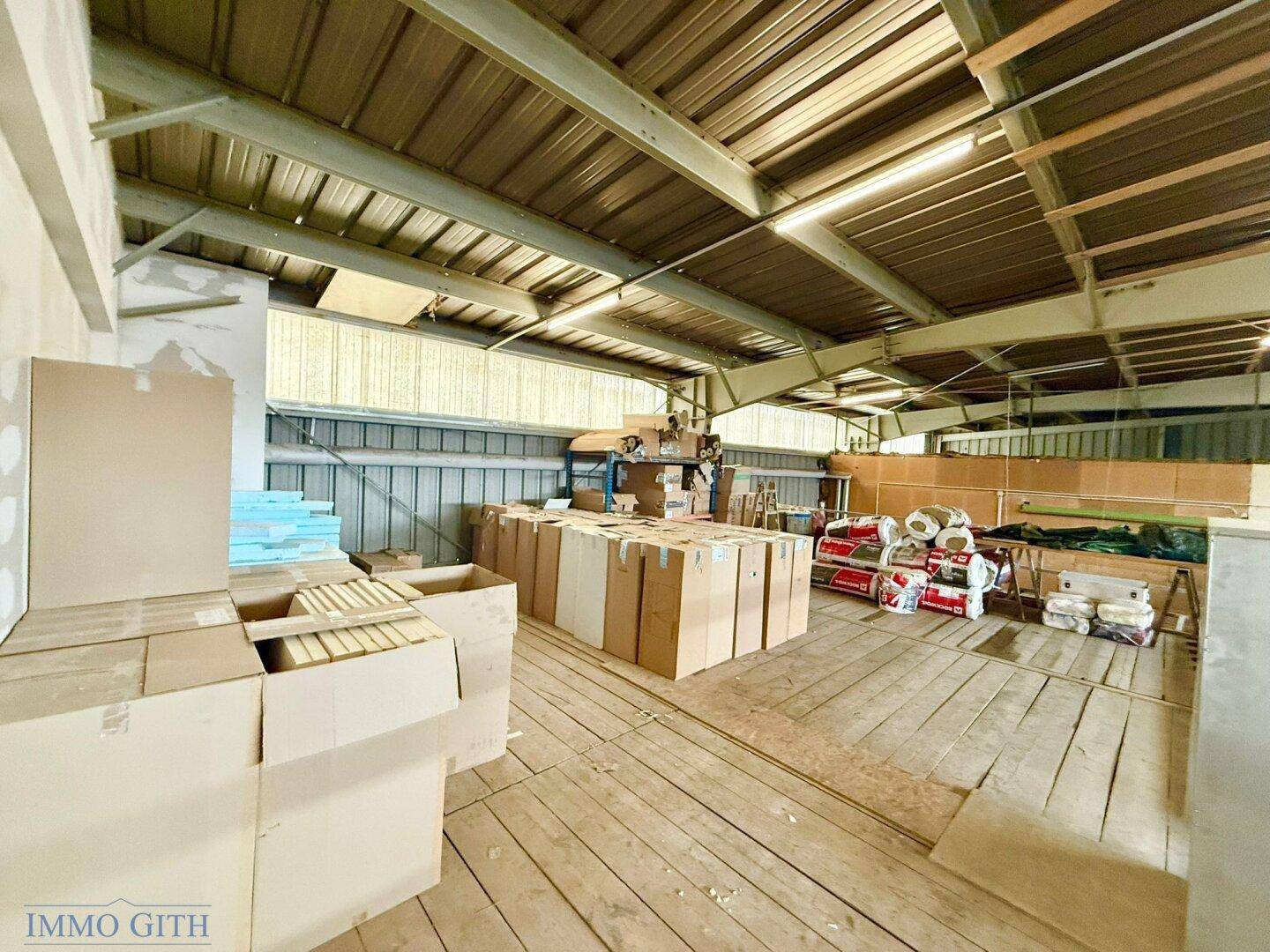 Geräumiges Zwischengeschoss mit Holzboden, vielen gestapelten Kartons und Blick auf die Halle.