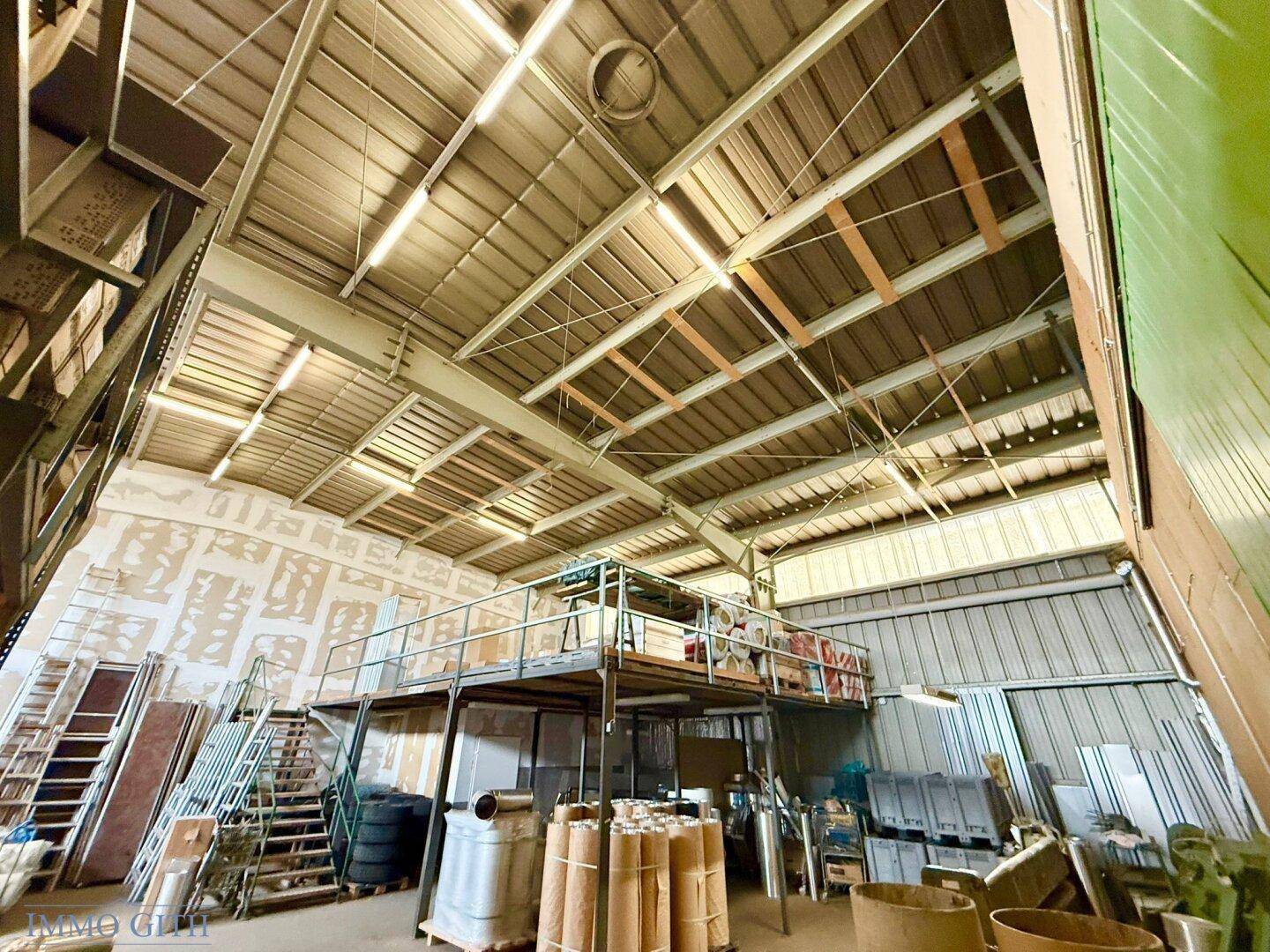 Weitläufige Lagerhalle mit hoher Decke, Zwischengeschoss und verschiedenen gelagerten Materialien.