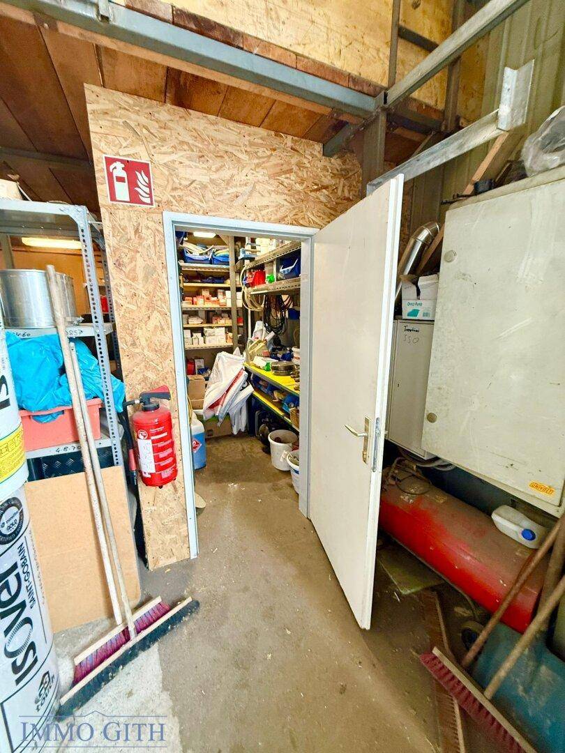Blick in einen kleinen Abstellraum oder Lagerraum mit Regalen voller verschiedener Gegenstände und Werkzeuge.