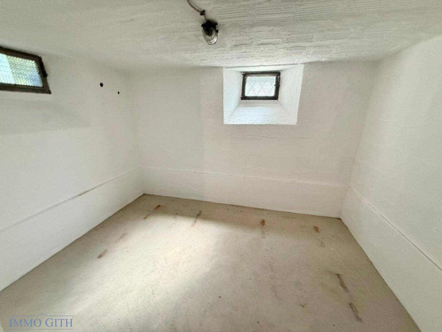 Heller Kellerraum mit kleinen Fenstern und Betonboden, bietet zusätzlichen Stauraum.